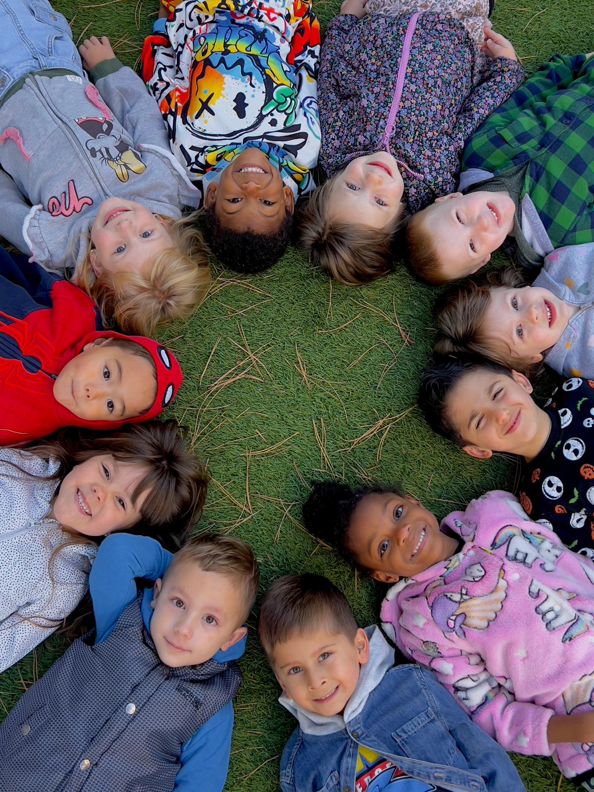Happy children laying down in a circle at Little Geniuses Learning Center